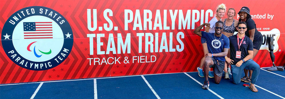 Adapted Athletics members posing in front of U.S. Paralympics Team Trials sign