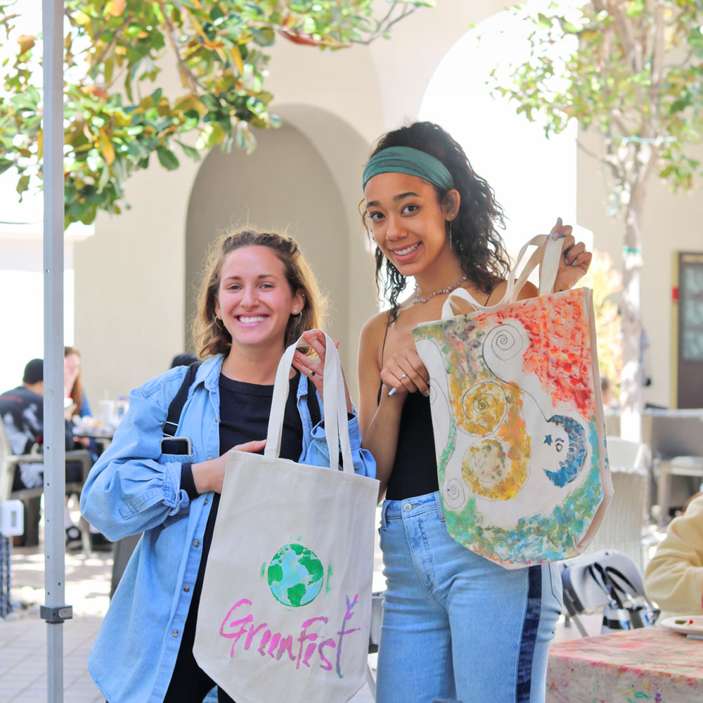 Two students with self-painted reusable canvas shopping bags