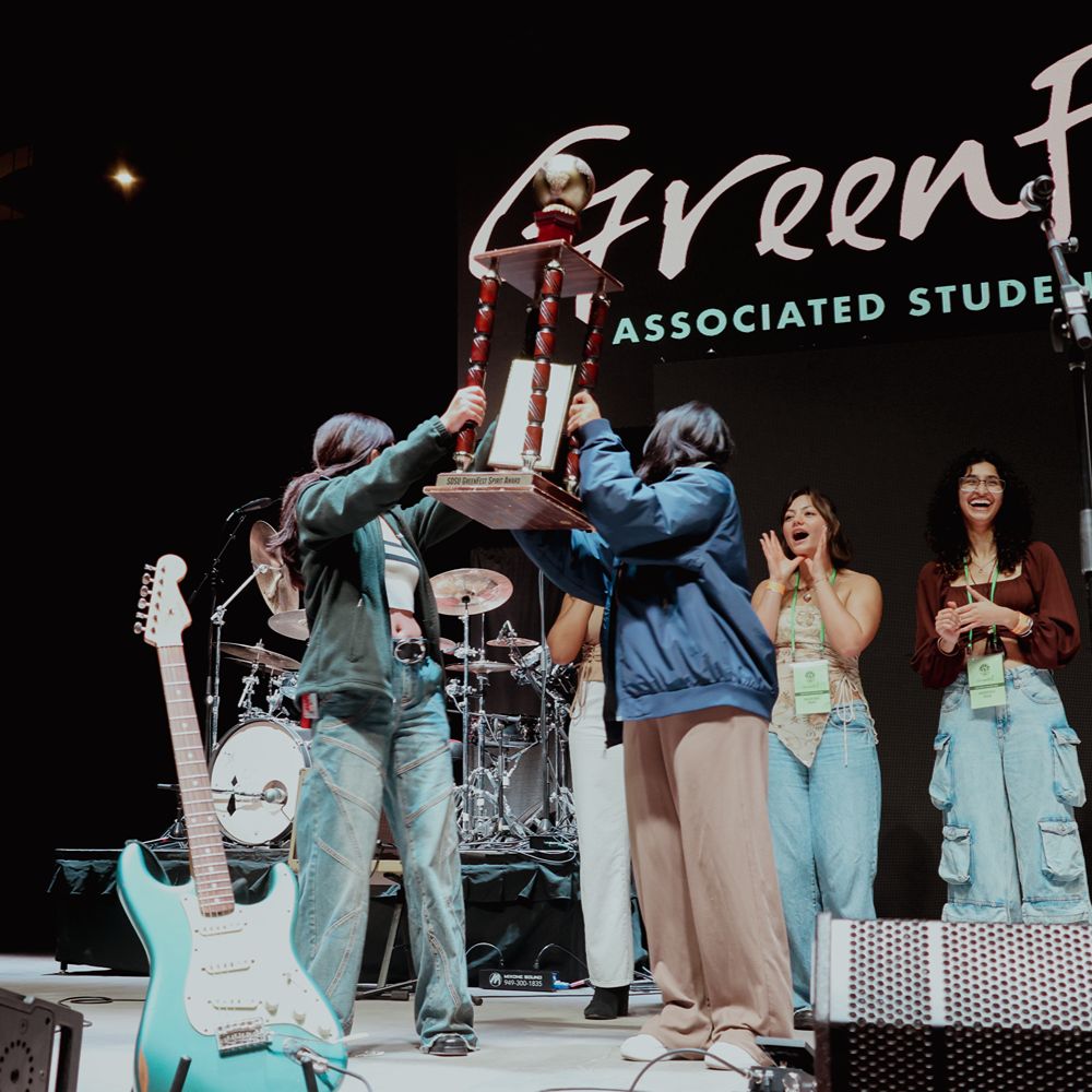 Several pairs of hands in a circle holding seedlings in soil