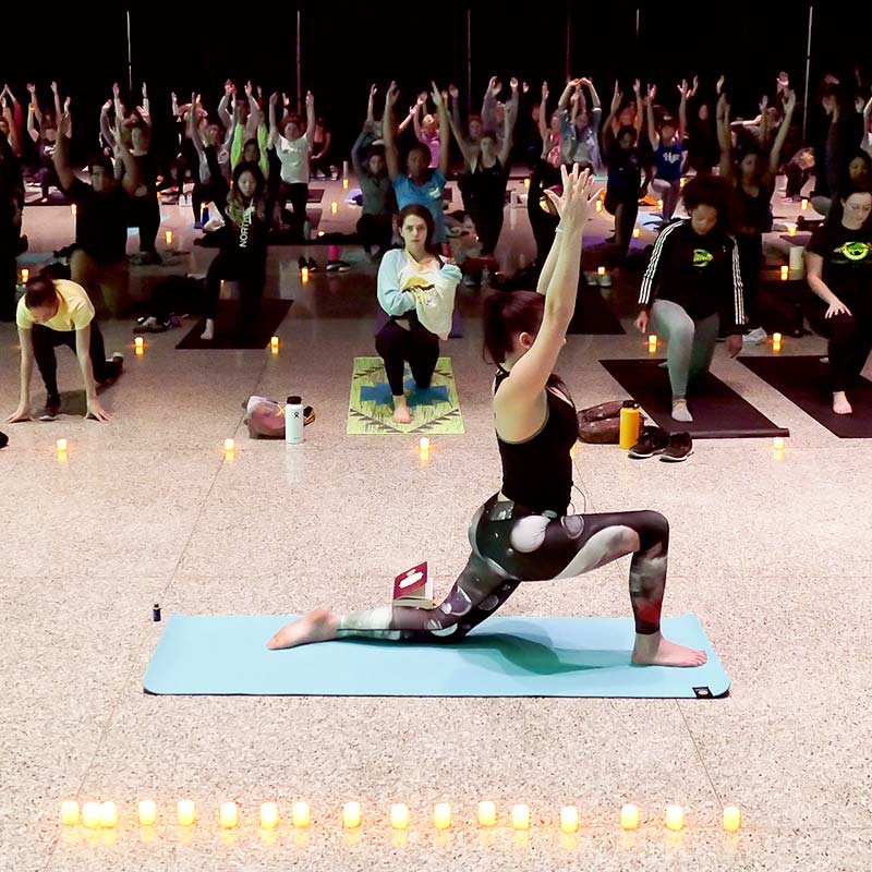 Large group of students doing candlelit yoga