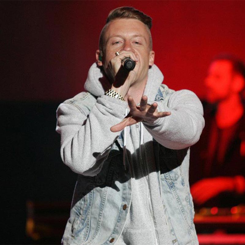 Macklemore holding microphone at a concert