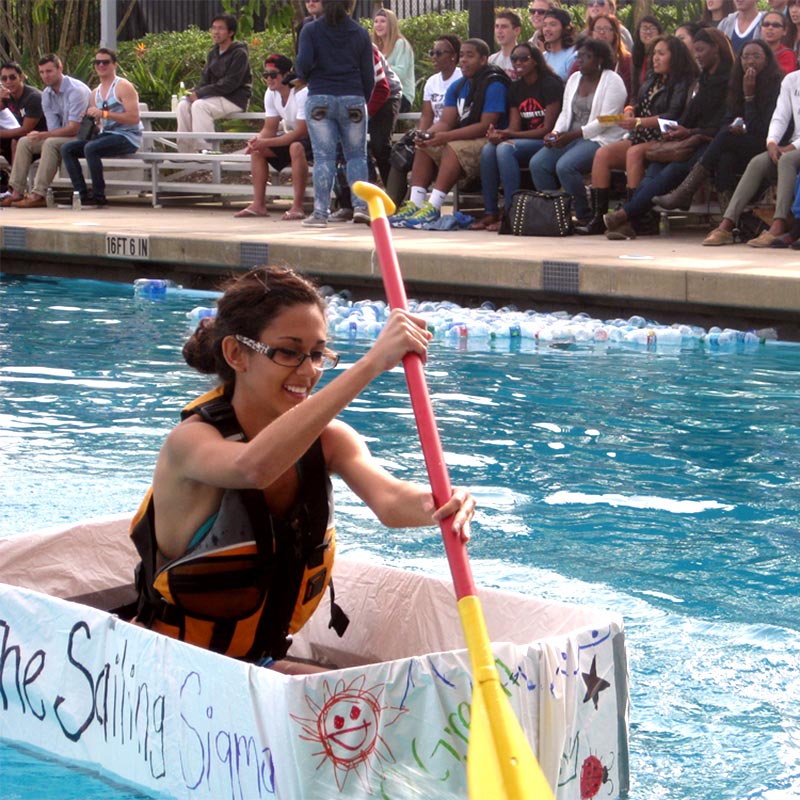 Girl rowing in markeshift cardboard box in a pool competition