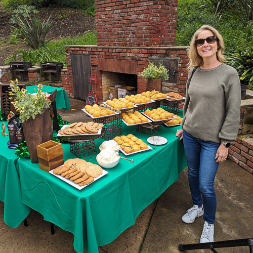 A member of GreenLove stands next to a table of baked goods.