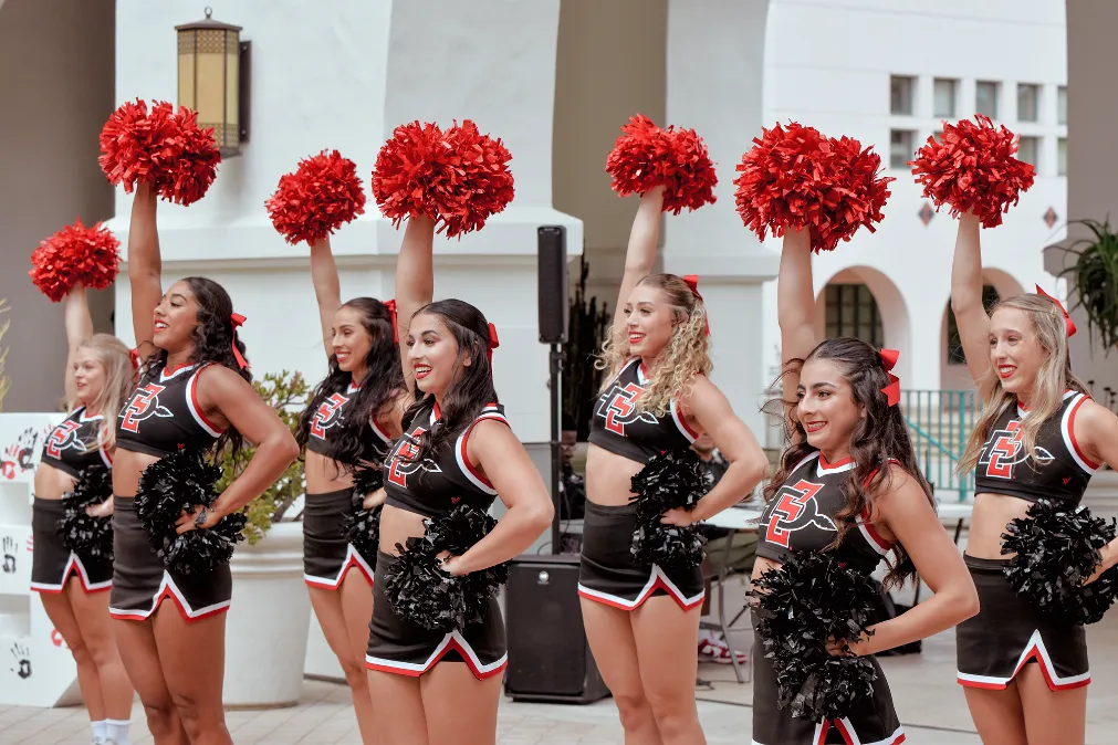 SDSU cheerleaders raising red pom-poms