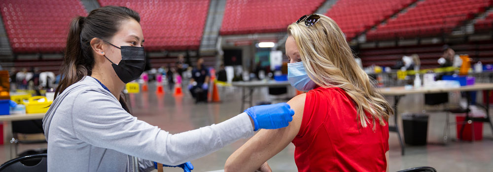 A woman receiving a Covid-19 vaccine shot inside Viejas Arena