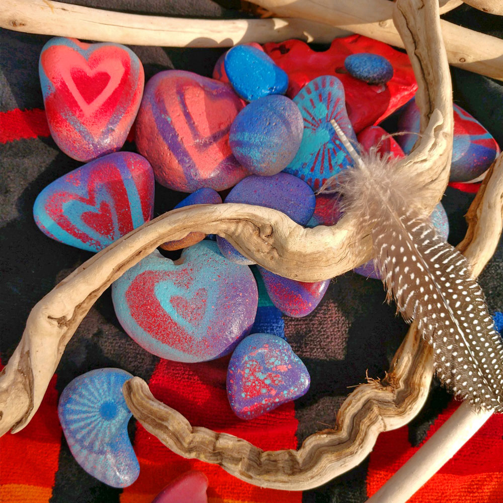 Rocks with painted hearts, sticks, feather