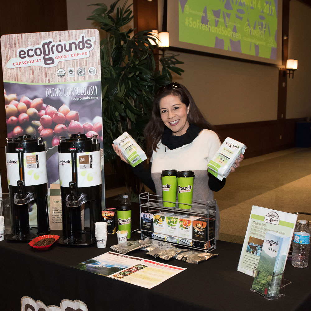 Representative of sustainable coffee business behind the display table with merchandise
