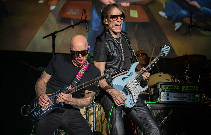 Two guitarists from Satch Vai Band performing on stage Photo