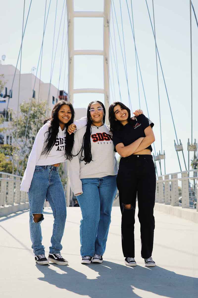 Three smiling SDSU students on the Union bridge