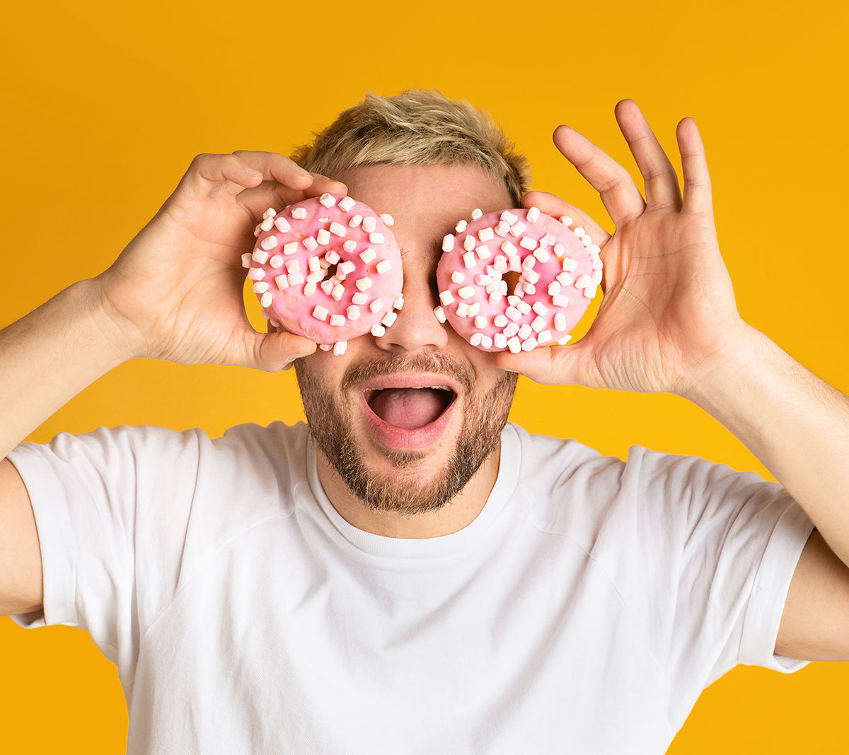 Young man holding two donuts in front of his face.?2024-07-02