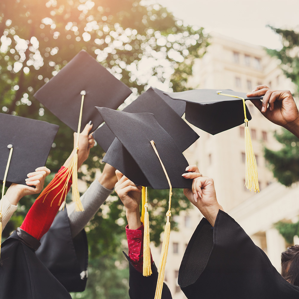 Graduates hold their caps in the air in celebration.