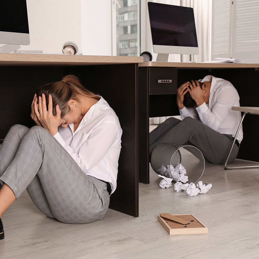 Office workers performing the cover step of earthquake response.