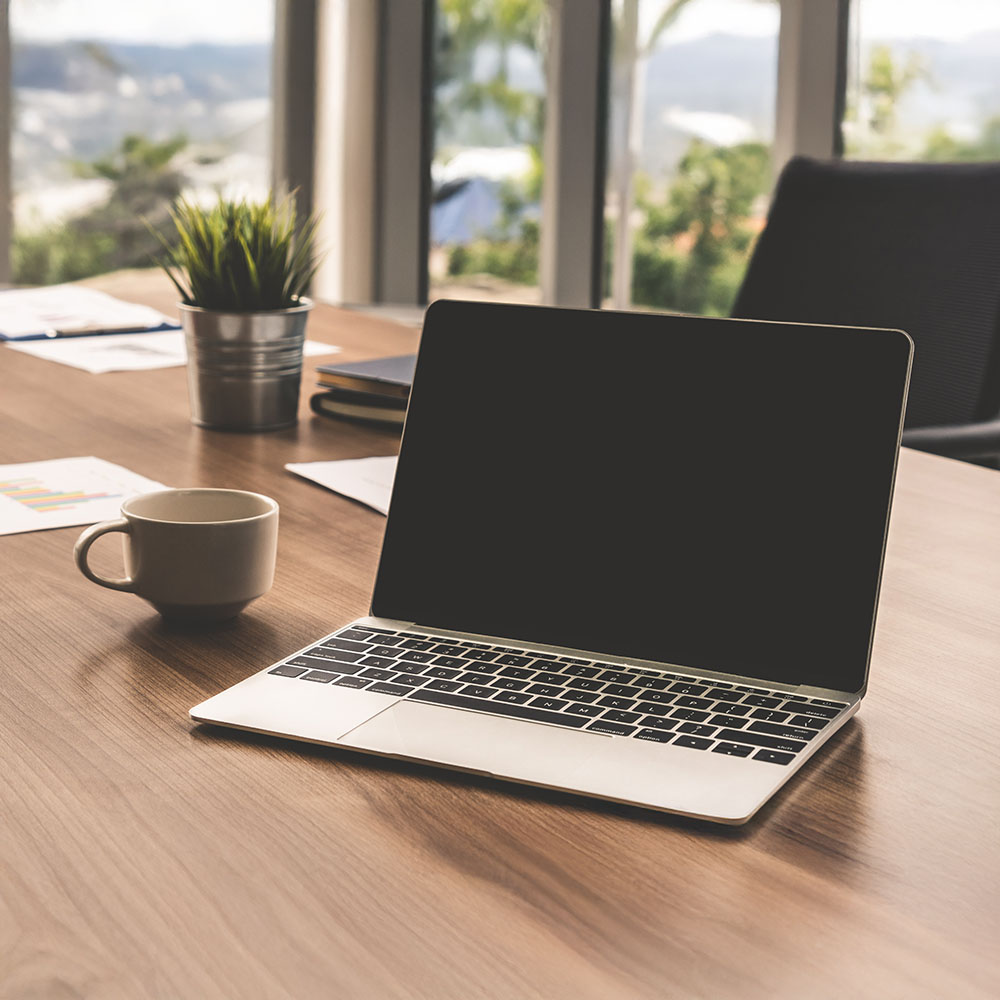 A laptop and a coffee on an office desk.