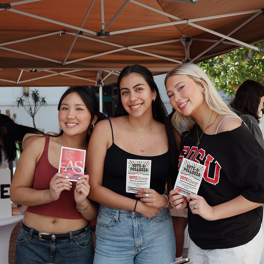 Three women holding up Vote-a-palooza flyers.