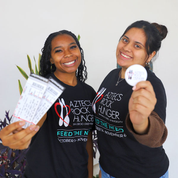 Two smiling ARH members showing event tickets