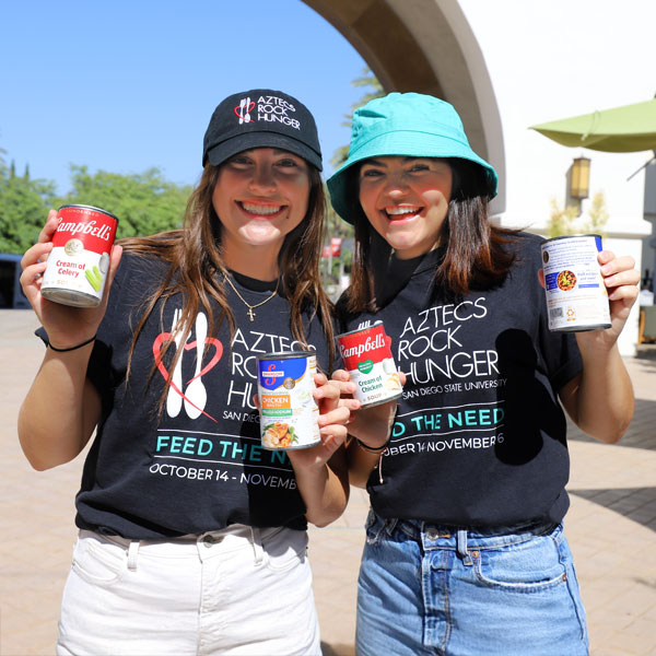 Two smiling ARH members holding up cans of food