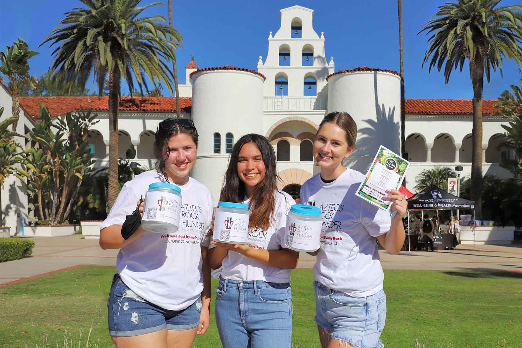 Three women holding ARH donation jars in front of Hepner Hall